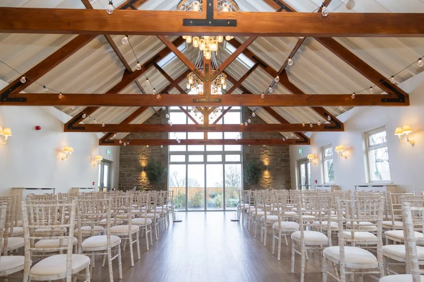 Wedding venue interior with rustic wooden beams, elegant lighting, and large window views in the Scottish Borders.