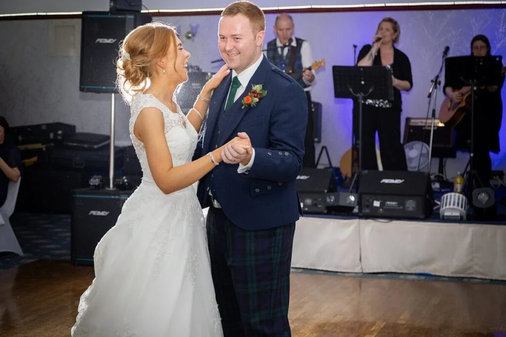 Wedding couple dancing at reception with band in background.